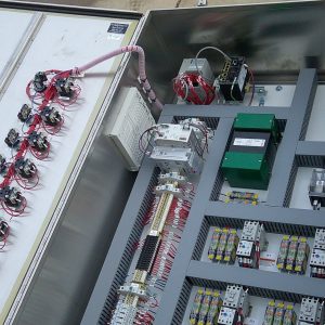 Open industrial electrical control panel with various relays, wiring, circuit breakers, and electronic components organized inside a metal enclosure for mining applications. Open industrial electrical control panel with various relays, wiring, circuit breakers, and electronic components organized inside a metal enclosure for mining applications.