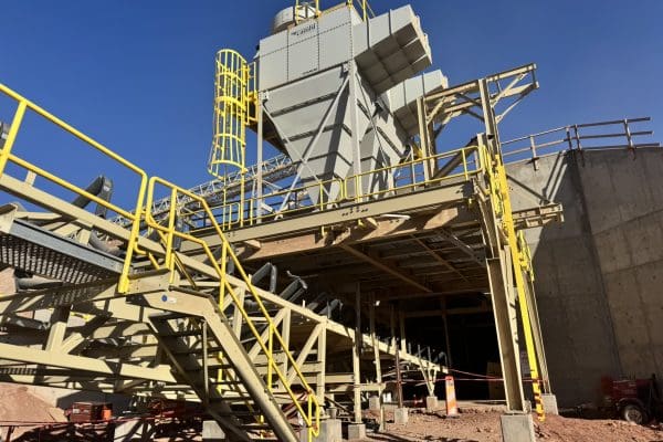 Large industrial mining structure with yellow safety railings, metal stairs, and machinery, set on a construction site under a clear blue sky. Large industrial mining structure with yellow safety railings, metal stairs, and machinery, set on a construction site under a clear blue sky.